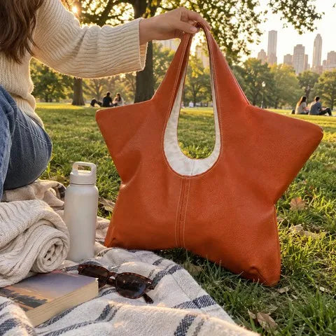 Orange star-shaped tote beside a picnic blanket in a city park