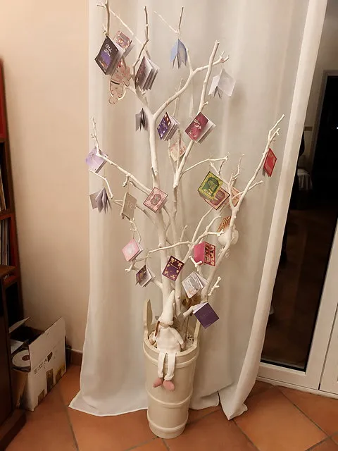 Miniature book ornaments displayed on a white decorative branch tree