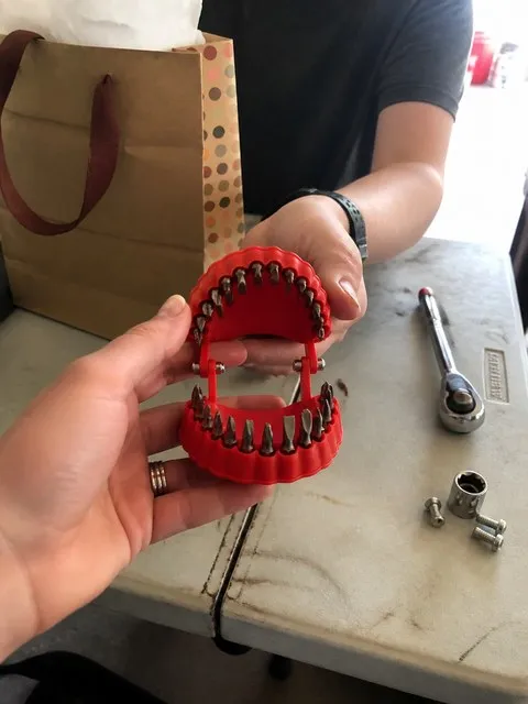 Two people exchanging the denture-shaped bit organizer as a workshop gift