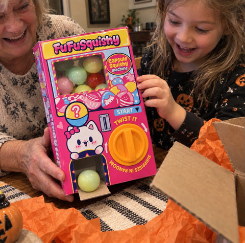 A grandmother and grandchild opening the capsule machine gift together