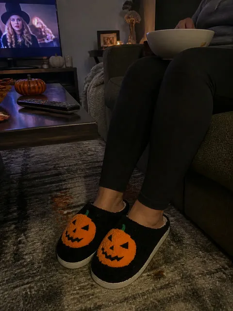 Black pumpkin slippers during a cozy movie night