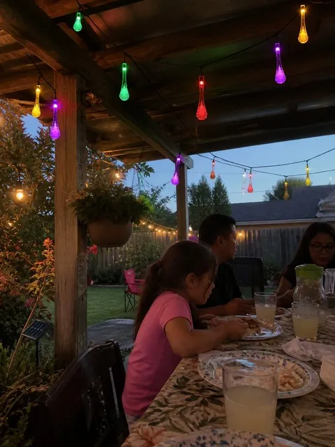Family dinner under multicolor waterdrop lights on a backyard pergola