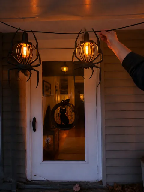 Spider string lights being adjusted over a front door