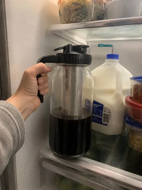 Cold-brew pitcher being placed on a refrigerator shelf