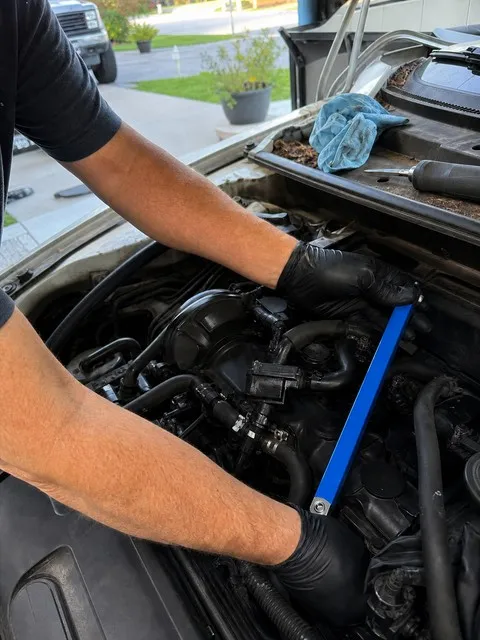 Mechanic using a blue offset extension wrench in a driveway engine bay