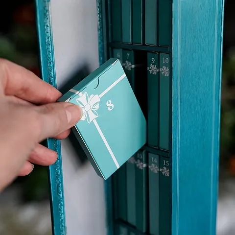Hand removing numbered box eight from the blue advent calendar