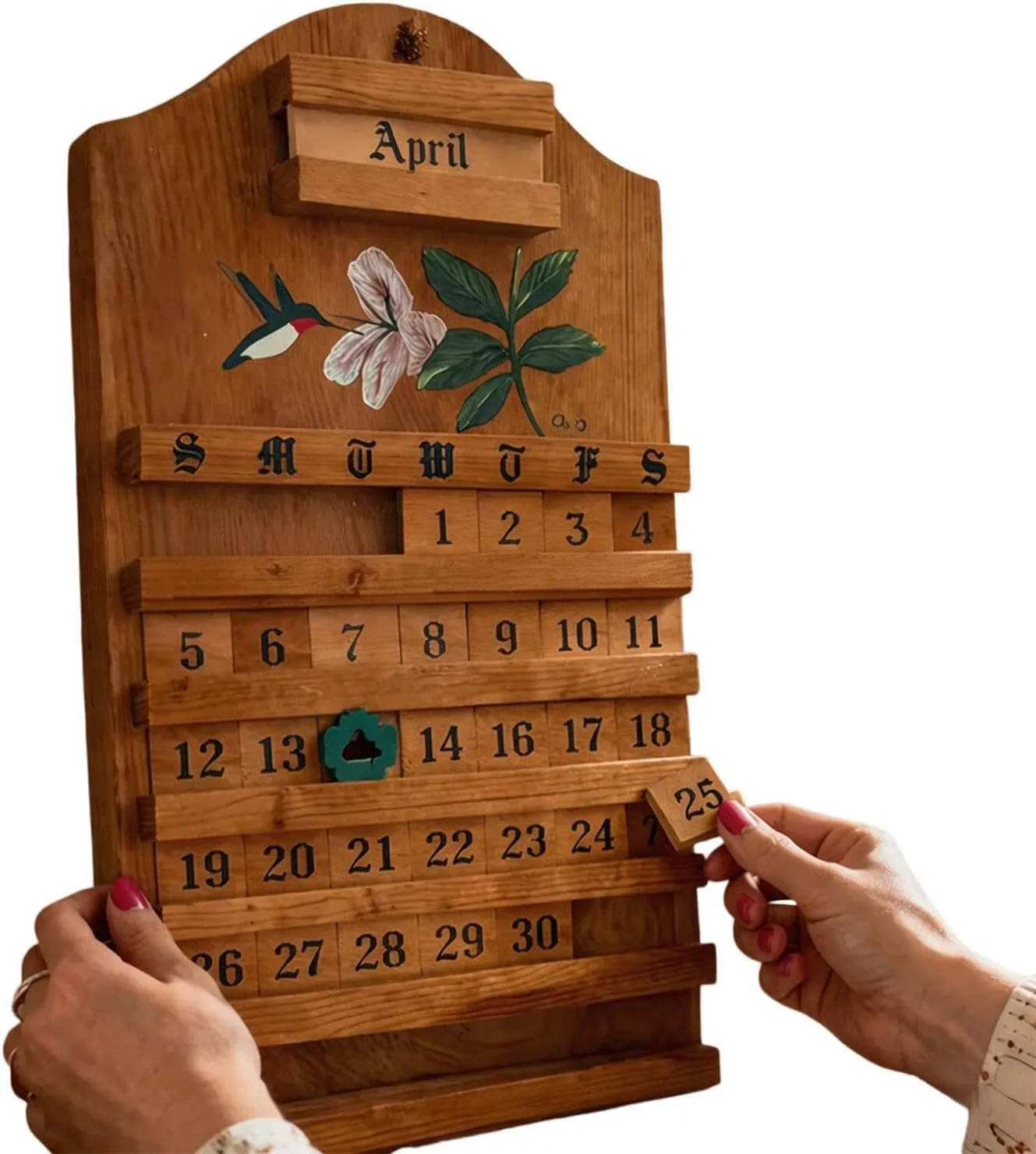 Hands placing a numbered tile into the wooden calendar