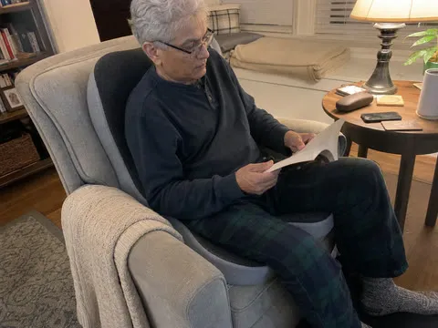 An older reader using the integrated cushion in a living-room chair