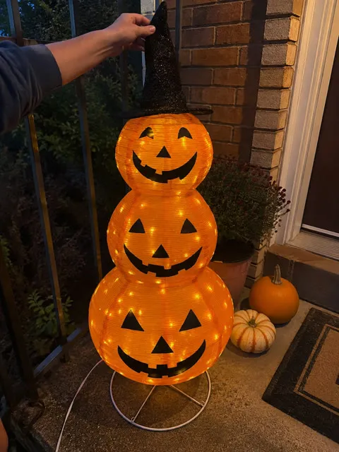 Glowing stacked pumpkin lantern on a brick porch