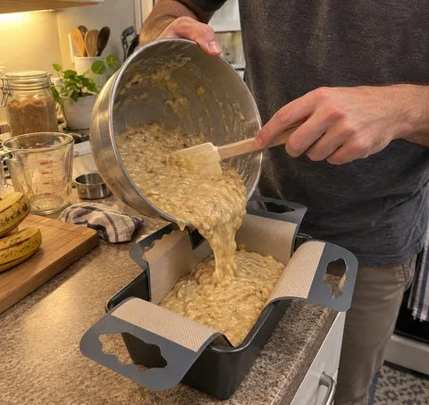 Batter being poured into a loaf pan lined with the sling
