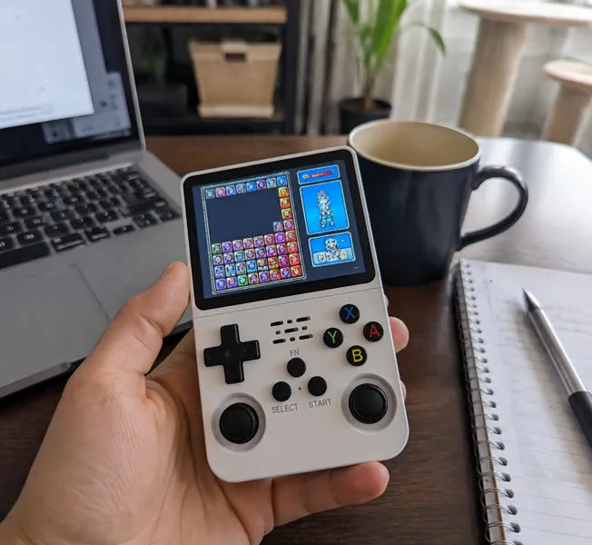 Handheld console beside a laptop in a home office