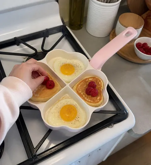 Four-section heart pan cooking eggs and pancakes in a home kitchen