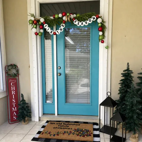Gold adjustable hanger holding Christmas garland above turquoise double doors
