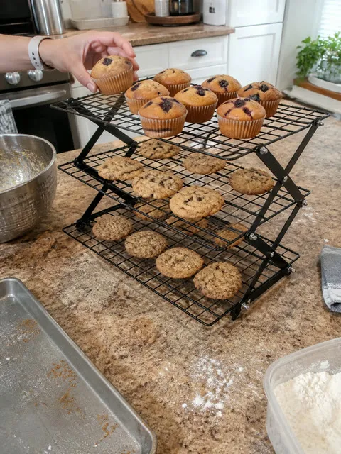 Three-tier cooling rack filled with muffins and cookies on a home kitchen island