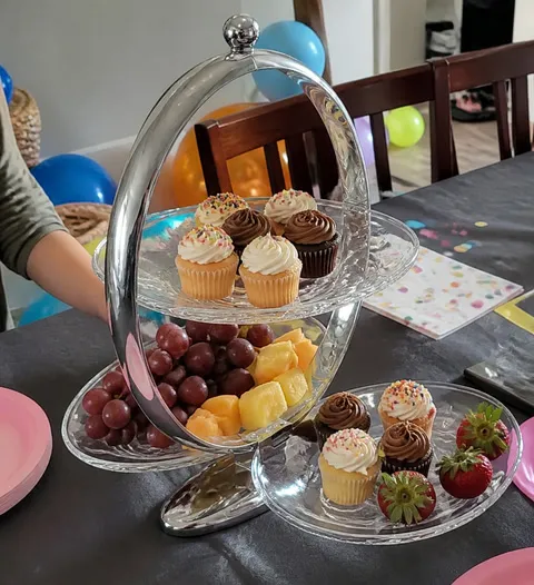 Serving stand arranged with cupcakes and fruit for a birthday table