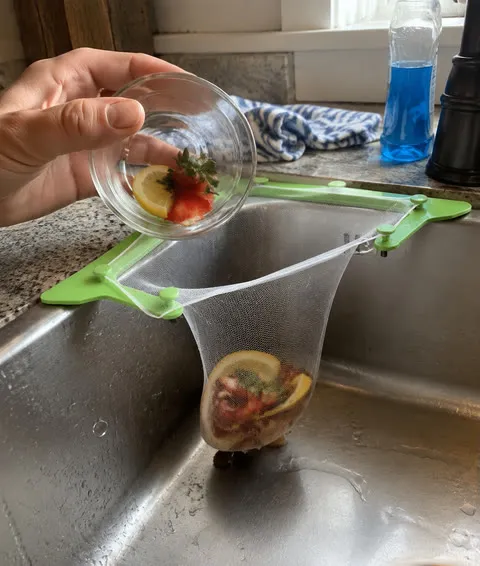 Fruit peels caught in a disposable mesh bag in a kitchen sink