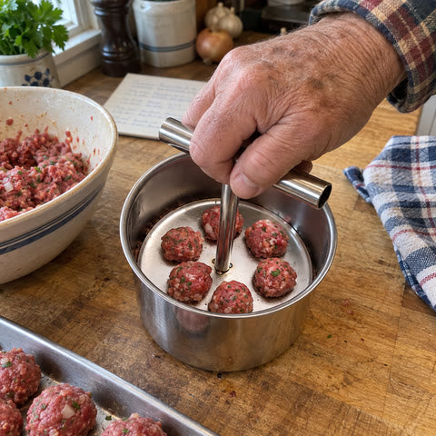 Home cook forming six meatballs on a butcher-block counter