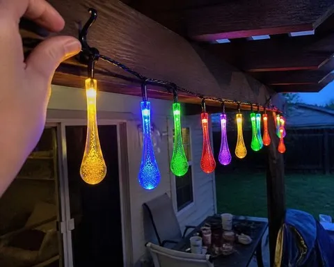 Multicolor teardrop lights hung from a backyard pergola in an everyday phone snapshot