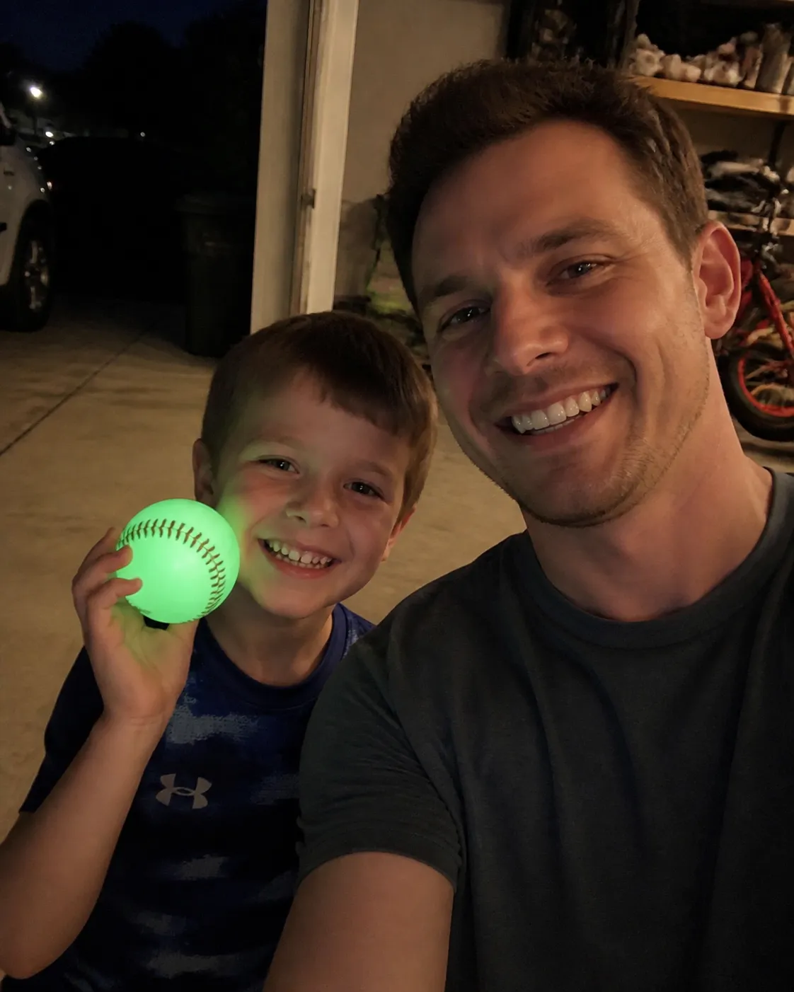 Family enjoying a glowing baseball near a garage