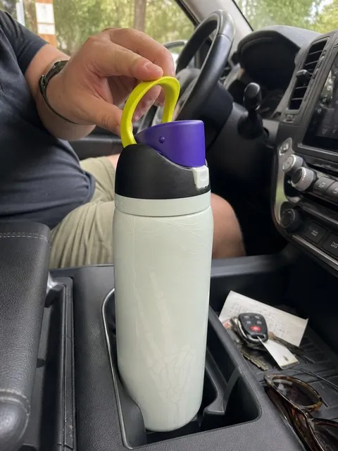 Pale skeleton bottle in a vehicle cup holder at a trailhead