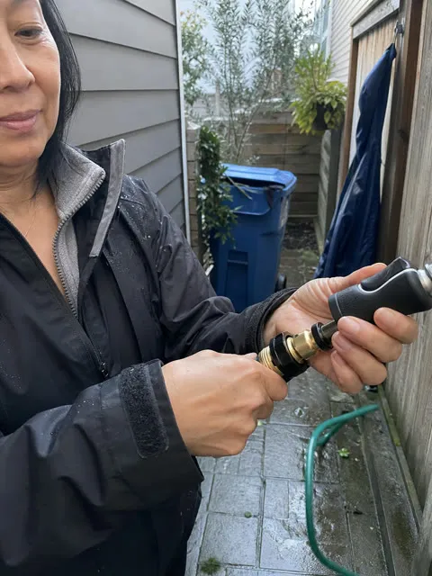 Woman disconnecting a hose nozzle after patio cleaning