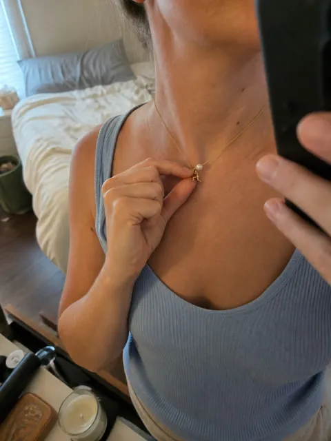 Gold-tone pearl pusher necklace worn in a casual bedroom mirror photo