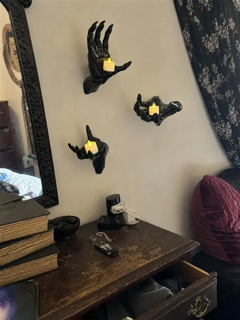 Black hand candle holders above a vintage bedroom dresser
