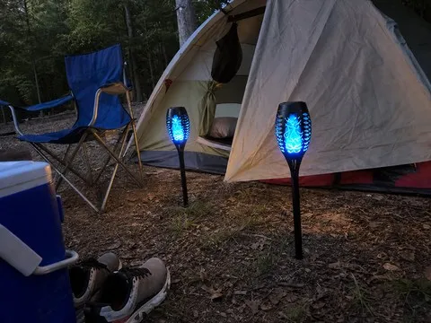 Two blue solar torches beside a campsite tent