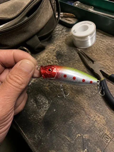 Angler rigging the popper at a fishing workbench