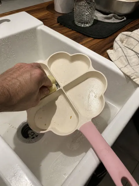 Four-section heart pan being cleaned with a soft sponge