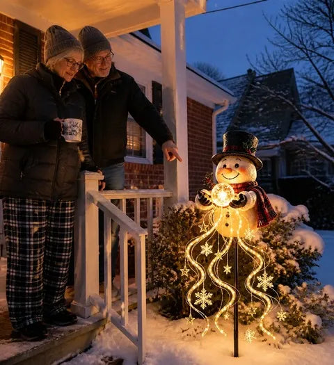 Older couple admiring the warm snowman garden light from a brick porch
