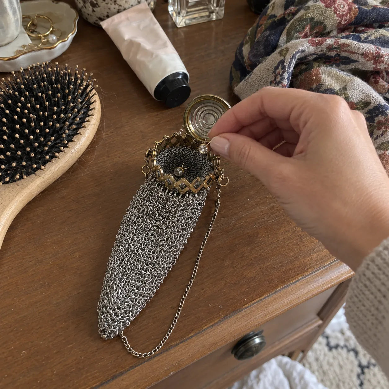 Open vintage mesh purse holding small earrings on a dresser