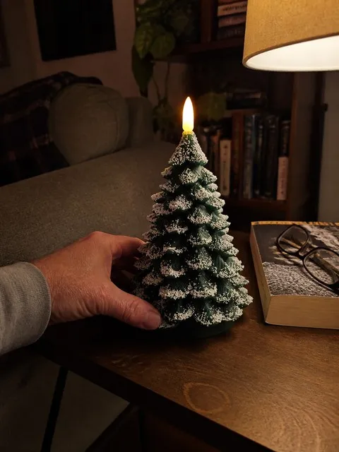 Tree candle glowing beside books and reading glasses
