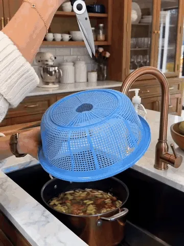 Stainless steel swan-hook sink strainer catching wet kitchen scraps while water drains into the sink