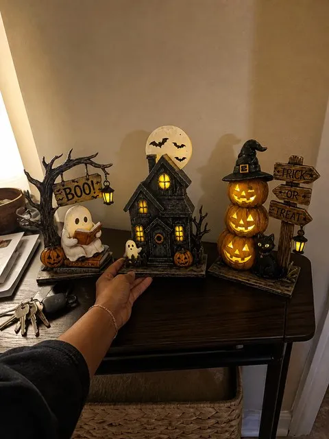 Three Halloween tabletop figurines on a lived-in apartment entry table
