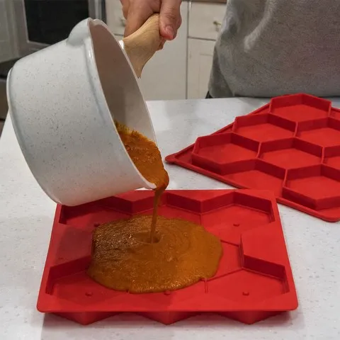 Homemade sauce being poured into a rectangular red silicone mold