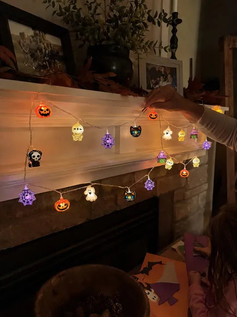 Halloween lights being arranged on a family mantel