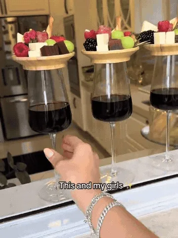 Bamboo appetizer toppers resting on wine glasses while holding bite-size snacks