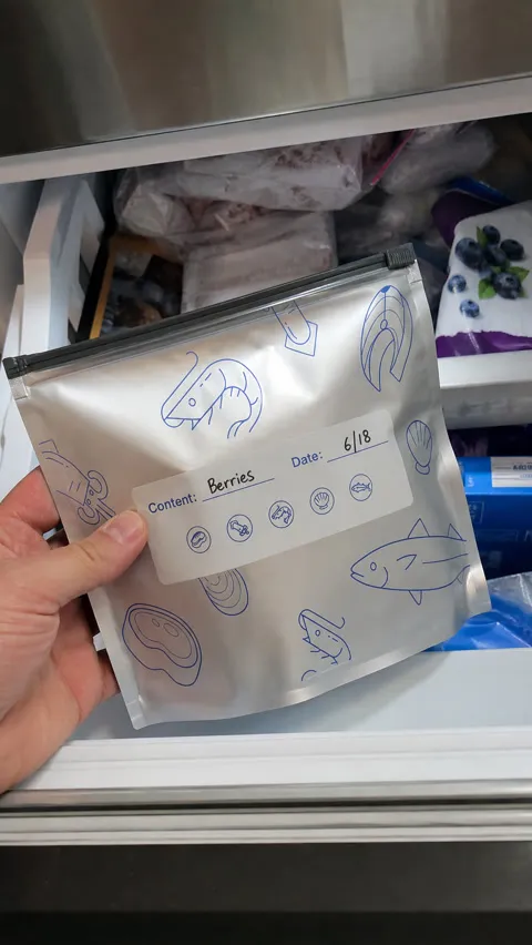 Hand retrieving a labeled foil pouch from a freezer drawer