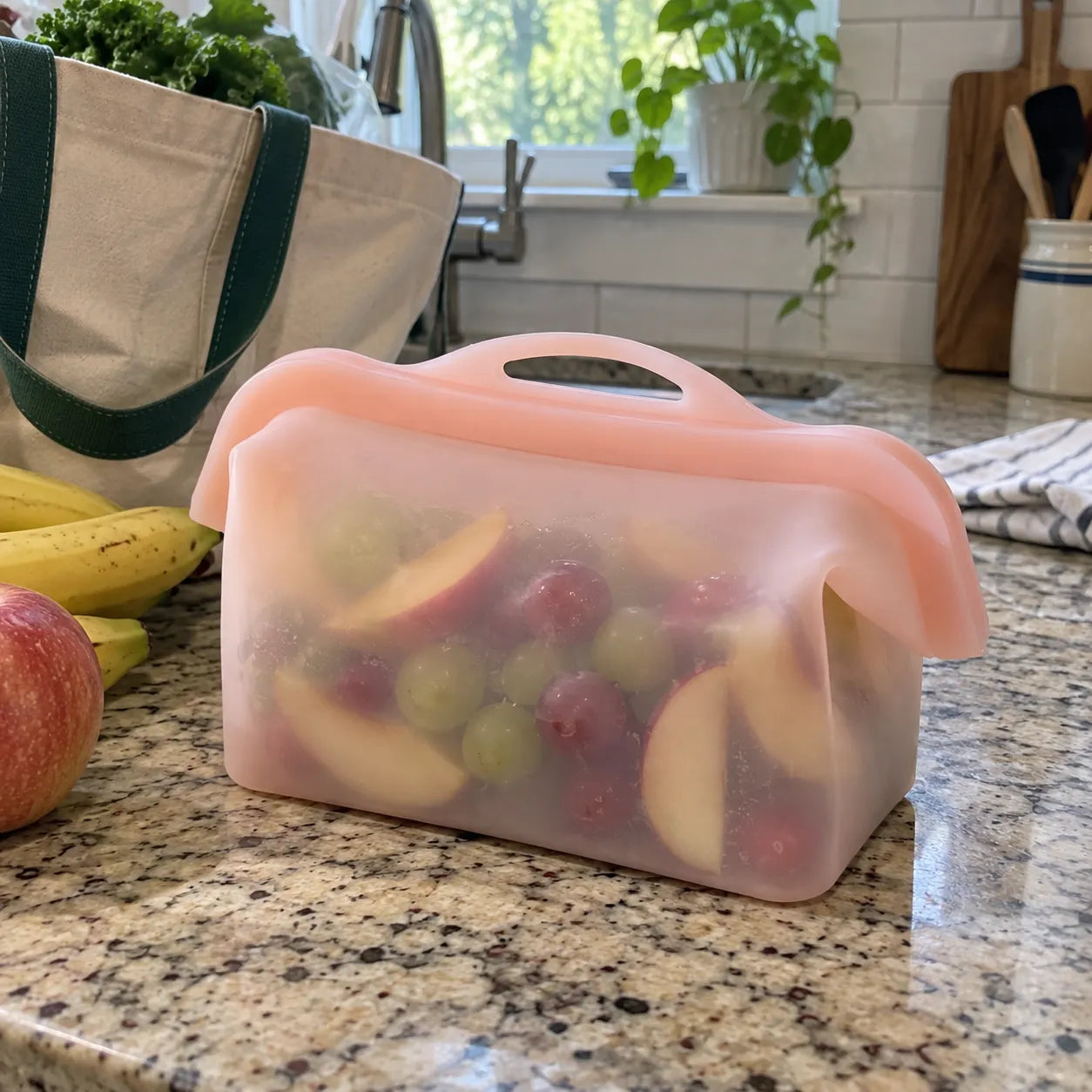 Closed silicone food storage bag holding fresh fruit on a kitchen counter