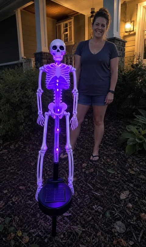 Purple solar skeleton yard stake in a front flower bed