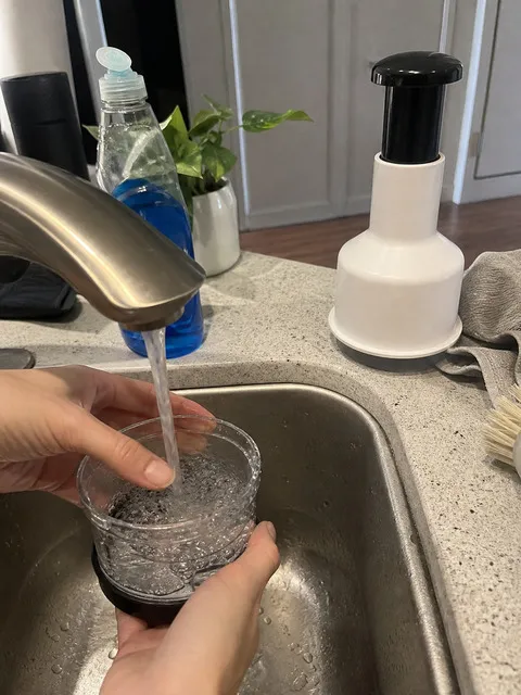 Rinsing the clear collection cup at a kitchen sink