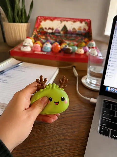 Hand squeezing a holiday dumpling character at a home office desk