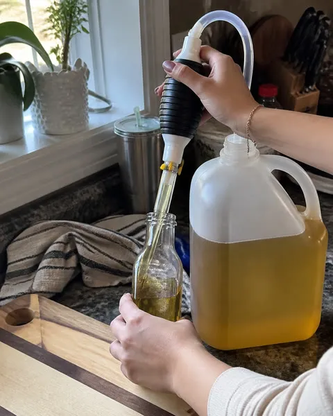 Hands transferring cooking oil into a smaller bottle