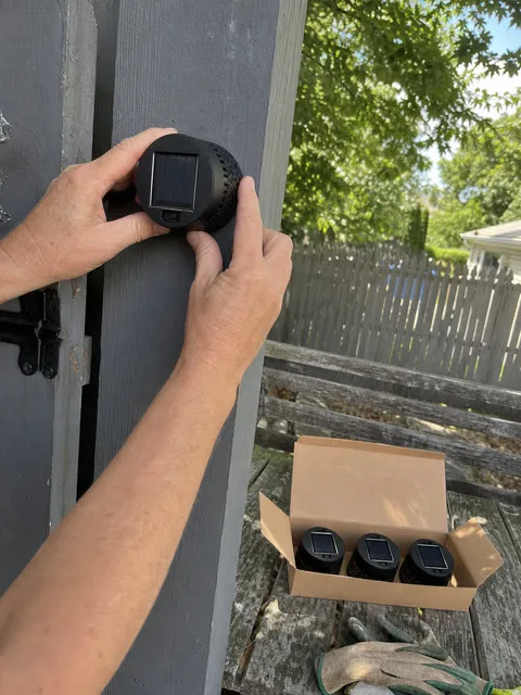 A customer installing one light from a four-piece solar wall light set