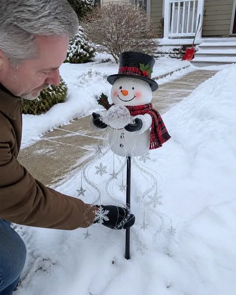 Snowman fountain light being positioned beside a snowy walkway in daylight