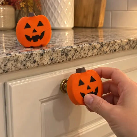 Hand placing a pumpkin cover on a drawer knob
