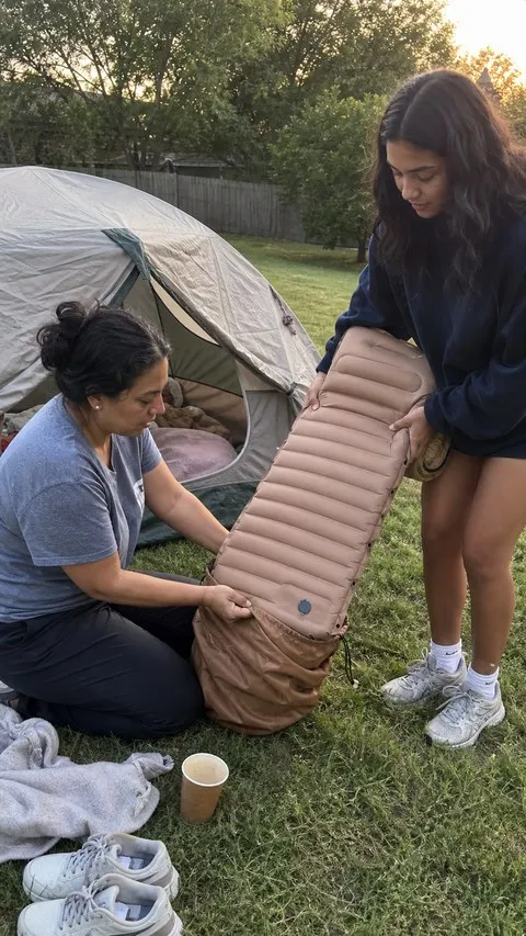 Customer-style snapshot of a family packing the camping mattress after a backyard campout