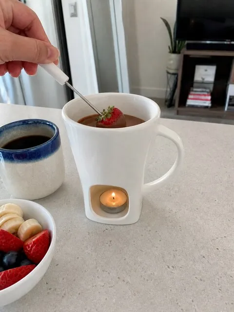 White chocolate fondue mug with fruit on a bright brunch counter