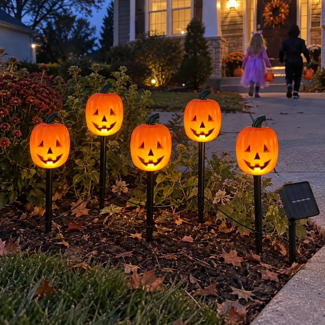Pumpkin pathway lights guiding costumed children toward a porch